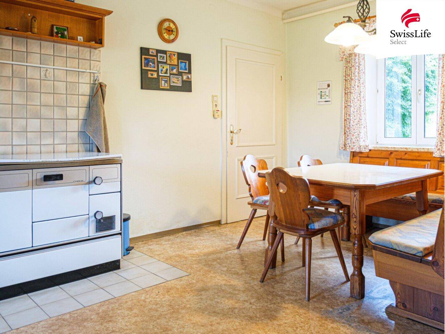 Gemütliche Wohnküche mit Holztisch, Eckbank und traditionellem Holzherd.