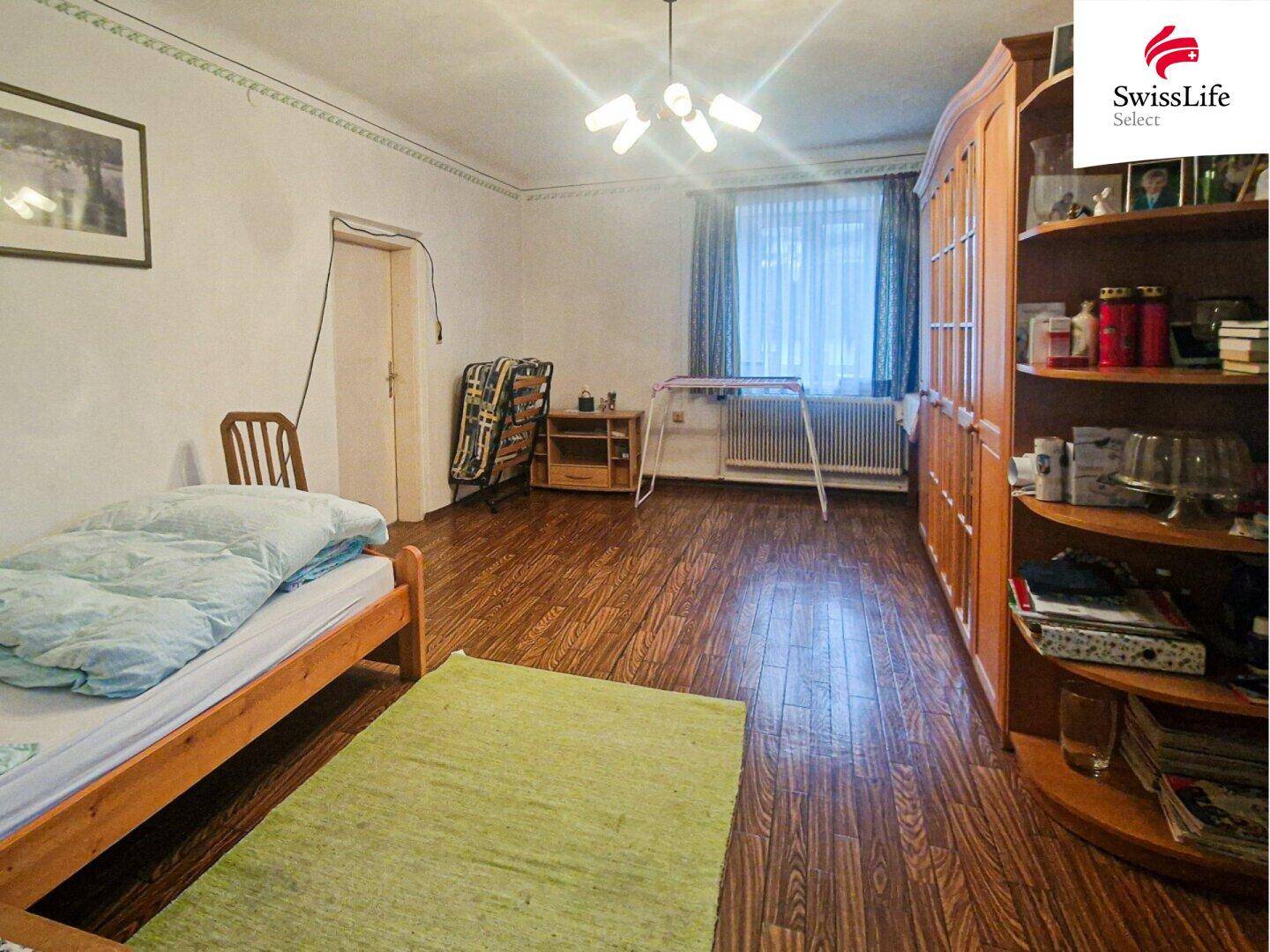 Schlafzimmer mit Holzboden, großem Kleiderschrank und Fenster mit Vorhängen.