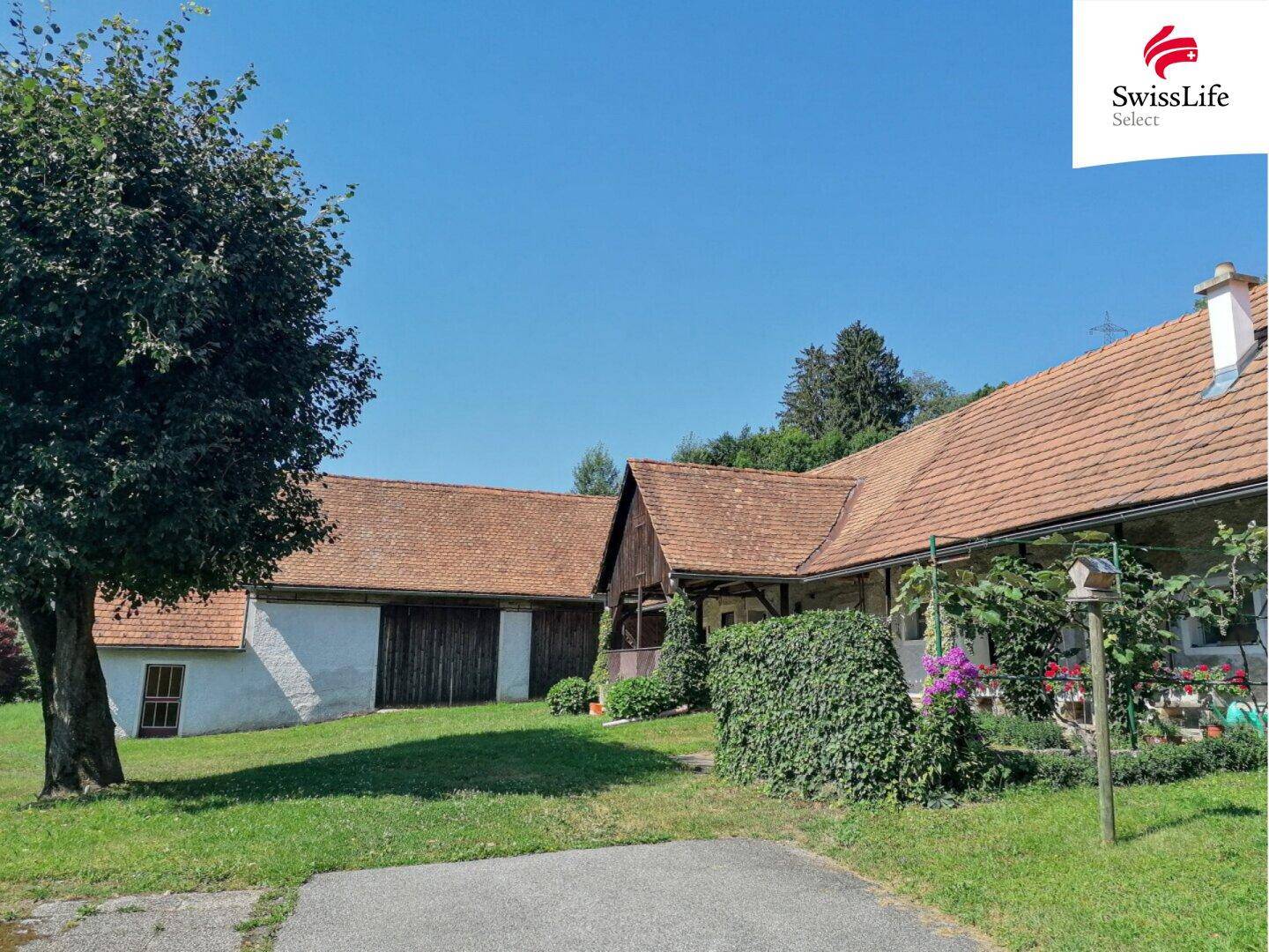 Historischer Bauernhof mit traditionellem Dach und gepflegtem Vorgartenbereich.