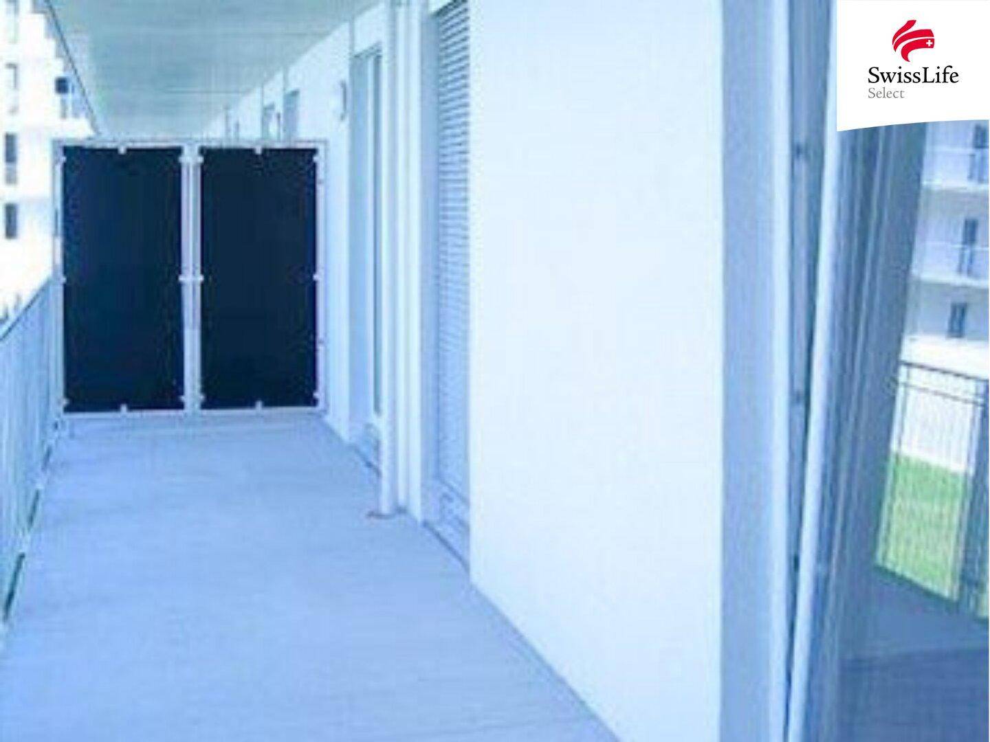 Langer, schmaler Balkon mit weißem Geländer und Blick auf die Umgebung.