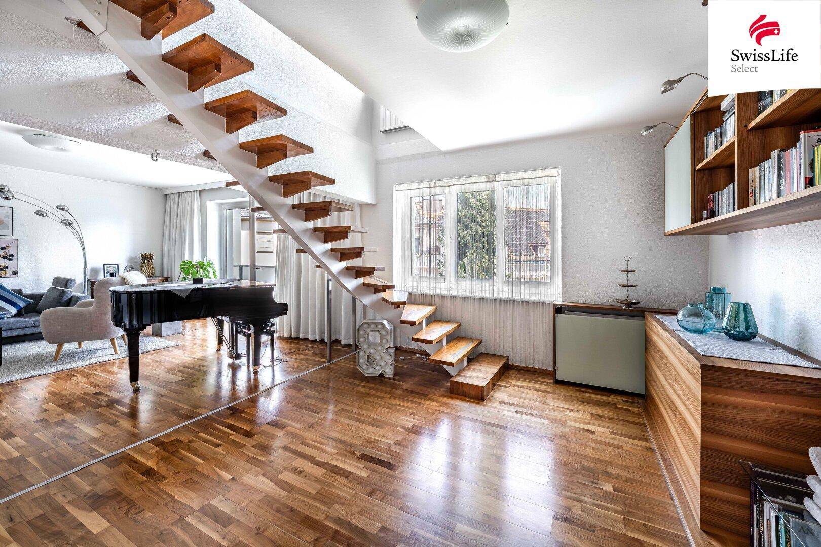 Geräumiges Wohnzimmer mit schwebender Holztreppe, Flügel und glänzendem Parkettboden.