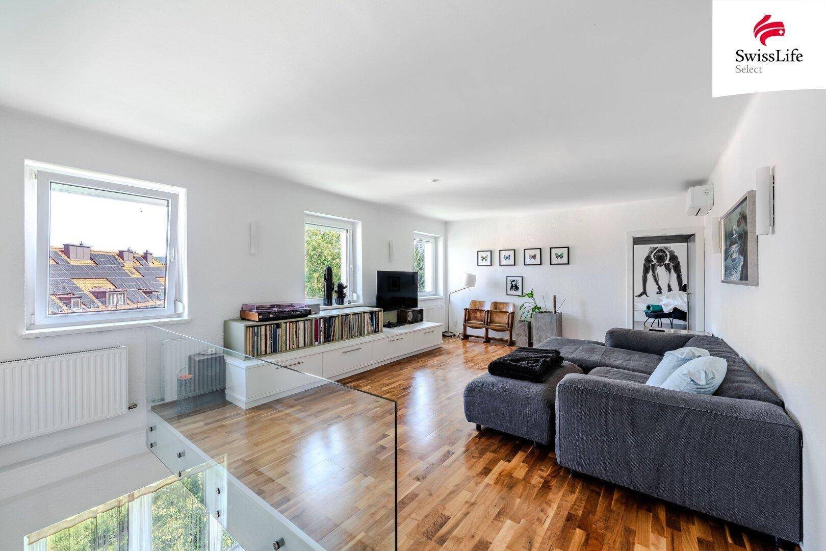 Moderner Wohnbereich mit großem Ecksofa, Mediencenter und Blick auf die Dächer der Stadt.
