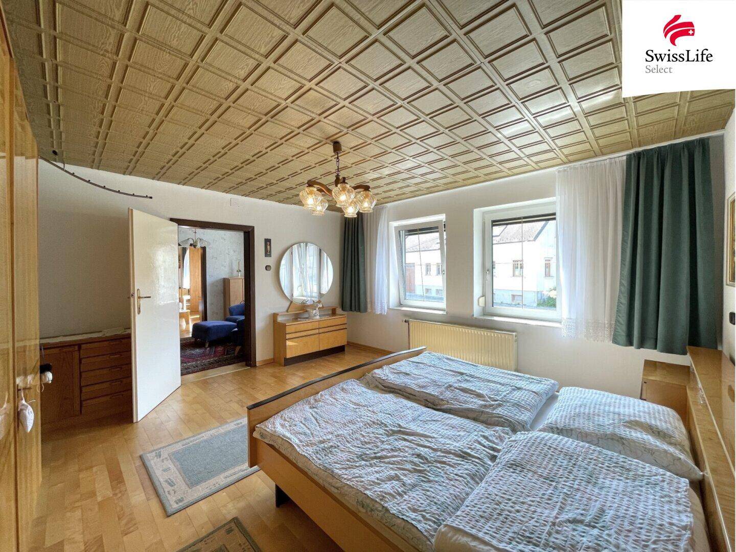 Schlafzimmer mit zwei Einzelbetten, Holzboden und einer auffälligen Holzdeckenverkleidung.