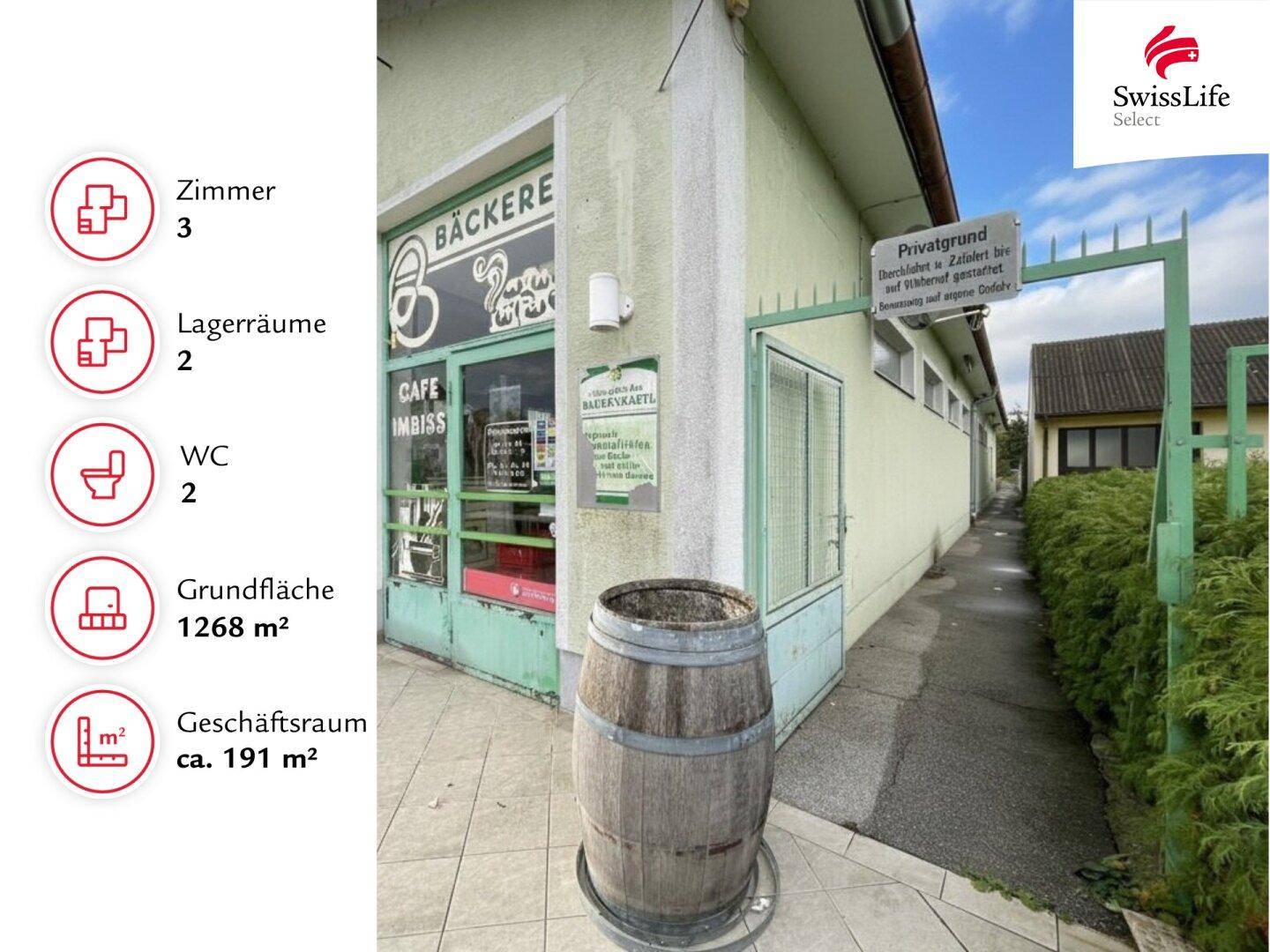 Seitenansicht der Gewerbeimmobilie mit schmalem Durchgang, Hecke und einem dekorativen Holzfass.