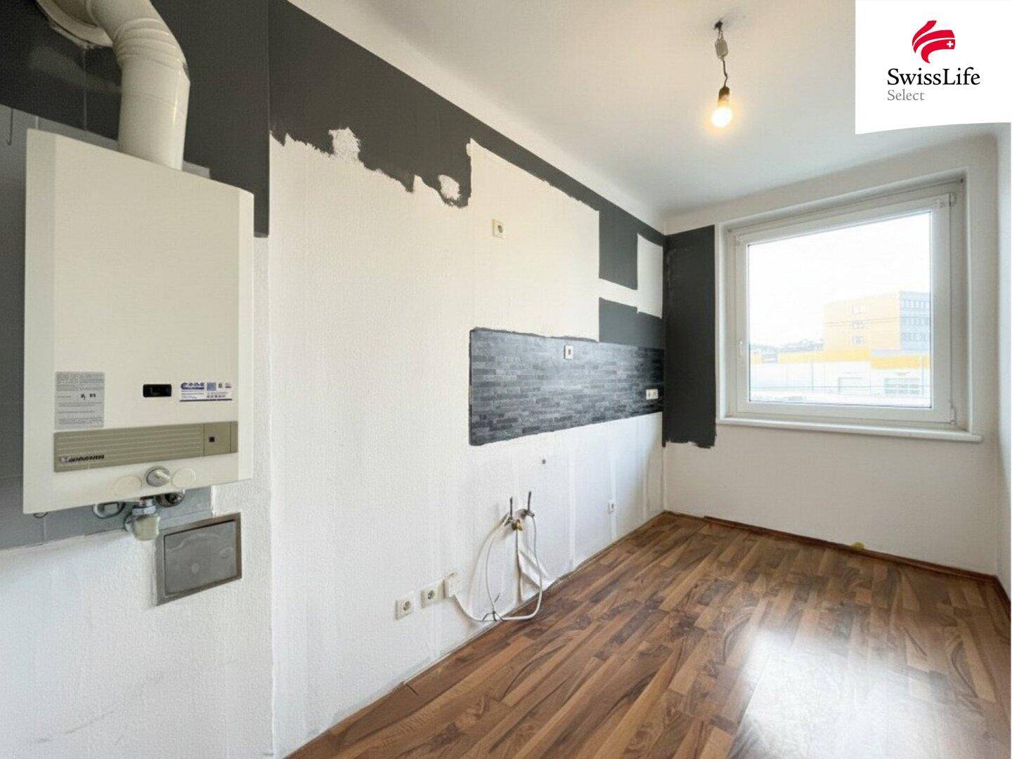 Leere Küche mit Gastherme und Fenster, bereit für den Einbau einer neuen Küchenzeile.