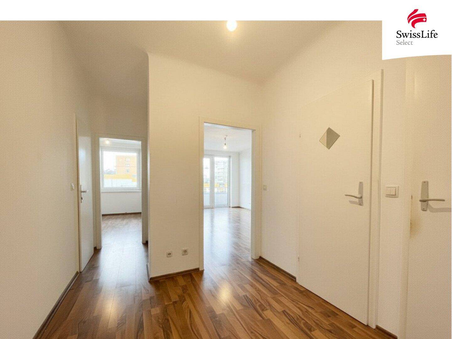 Langer Flur mit Holzfußboden, der zu verschiedenen Zimmern der Wohnung führt.