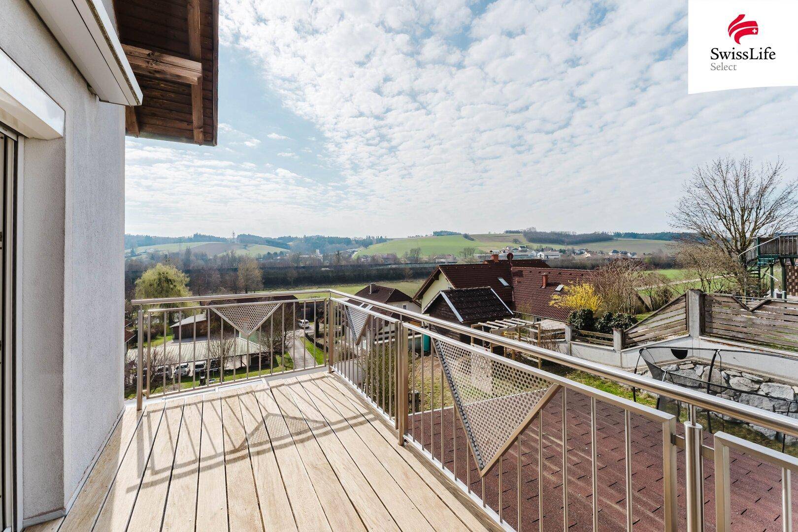 Großer Balkon mit Holzboden, Metallgeländer und weitem Blick über die Landschaft.