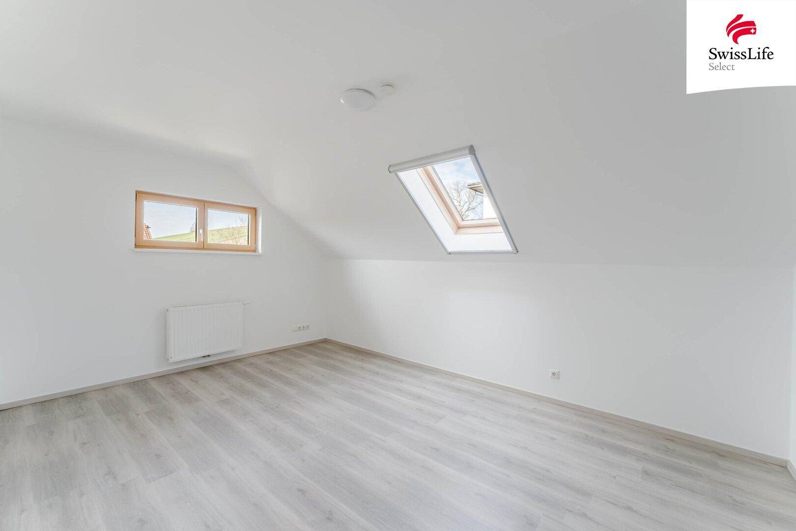 Geräumiges Dachzimmer mit hellem Laminatboden und zwei Fenstern für viel Licht.