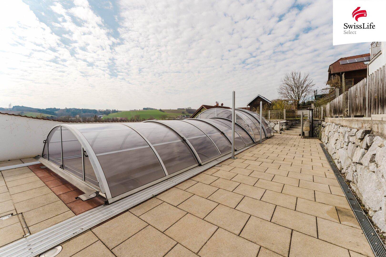 Großer Poolbereich mit verschiebbarer Überdachung und gepflasterter Terrasse.