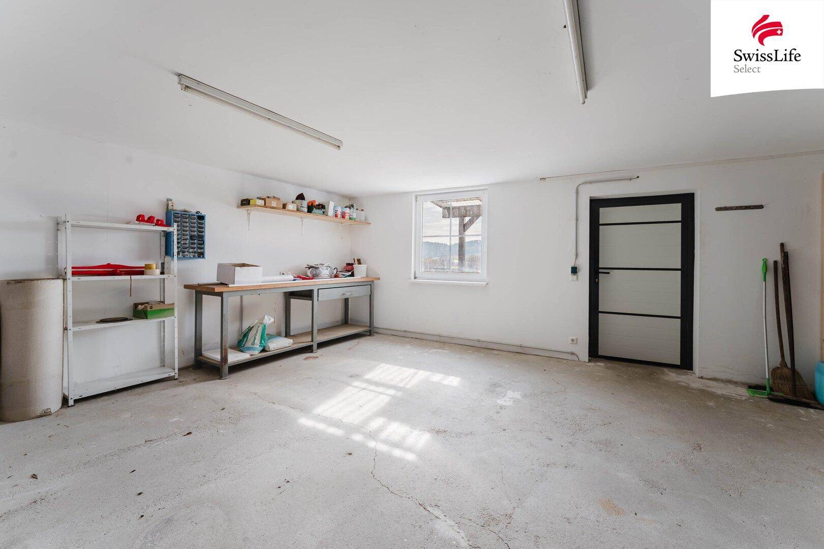 Geräumiger Werkstattraum mit Betonboden, Fenster und viel Stauraum.