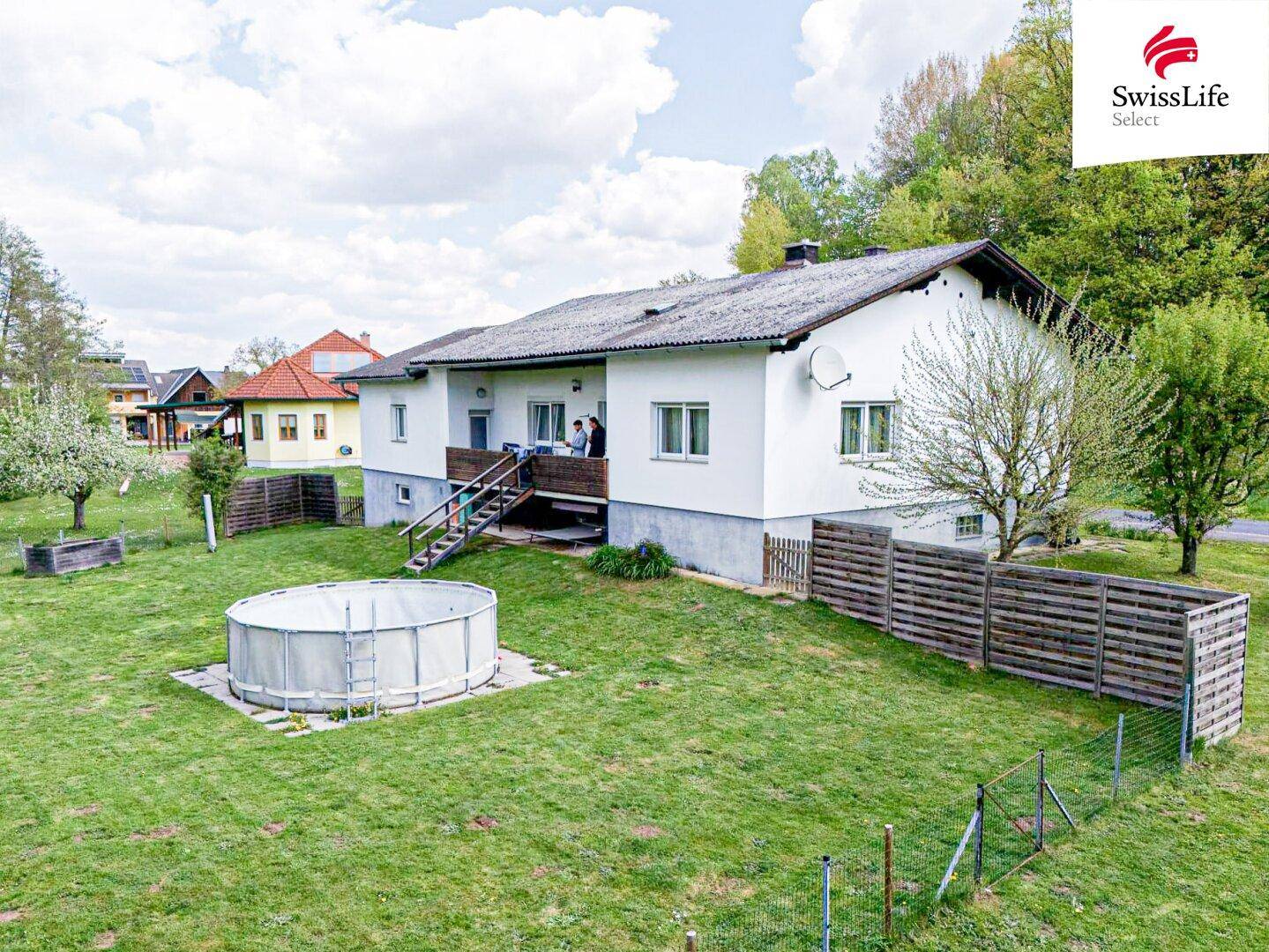 Großer Gartenbereich mit Aufstellpool, Rasenfläche und einer kleinen Terrasse hinter dem Einfamilienhaus.