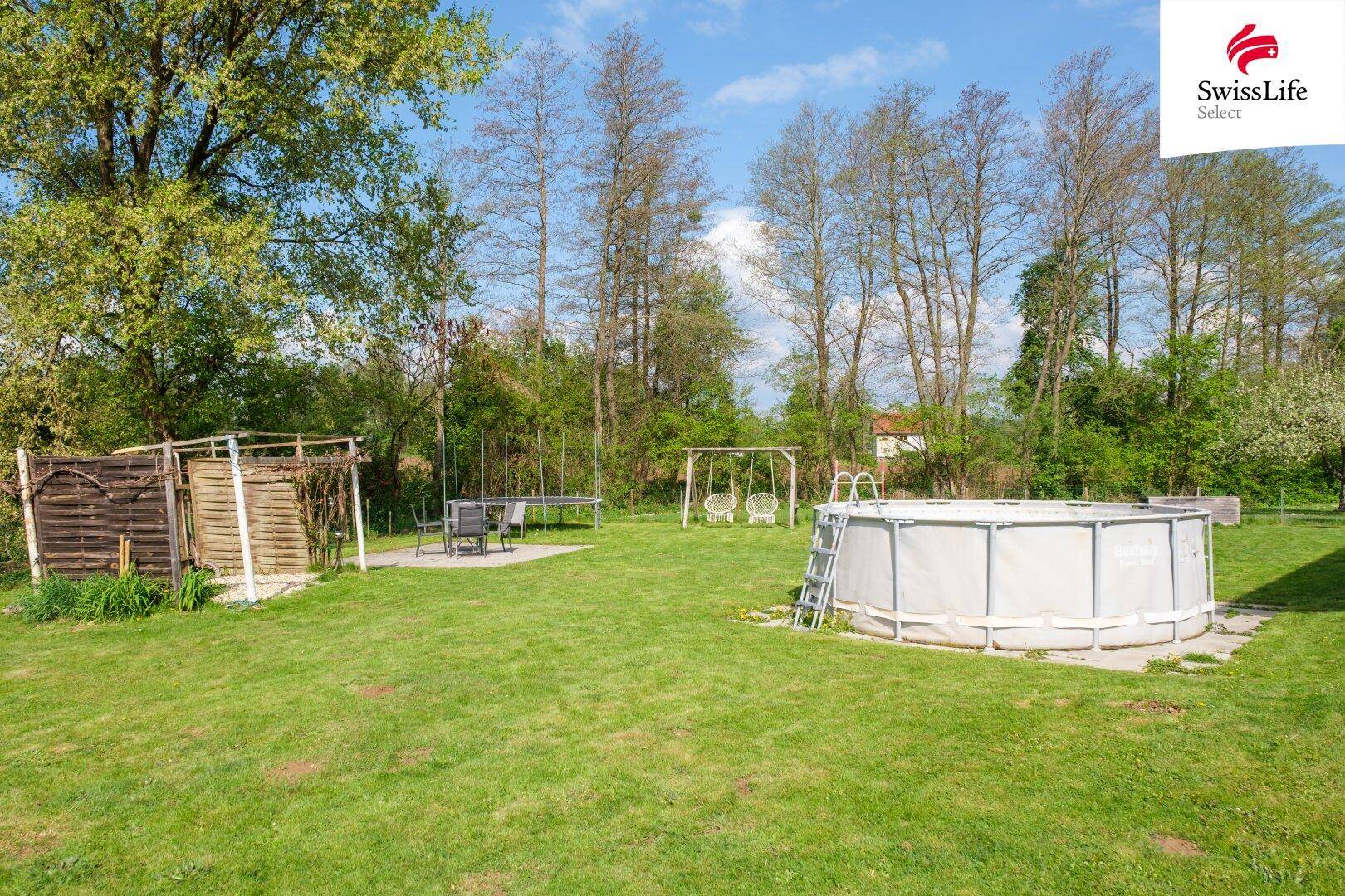 Weitläufiger Garten mit Aufstellpool, Trampolin und Schaukeln, ideal für Familienaktivitäten im Freien.