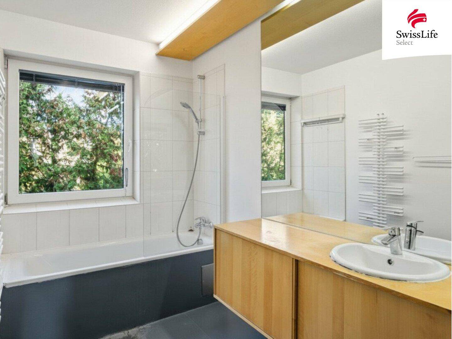Helles Badezimmer mit Badewanne, Fenster und beheiztem Handtuchhalter für Komfort.