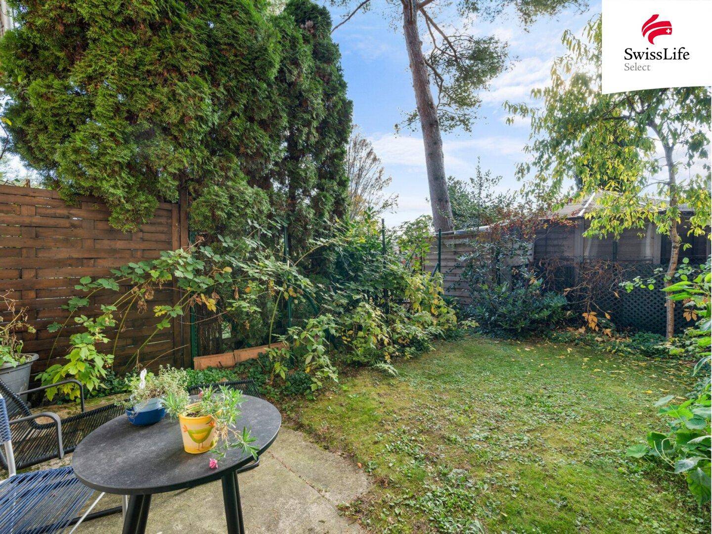 Kleiner, gepflegter Garten mit Rasenfläche und Sitzgelegenheit im Freien.
