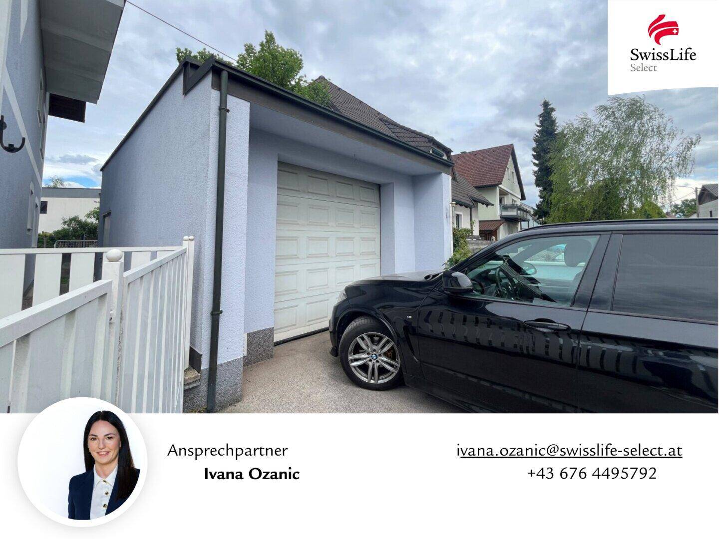 Separate Garage mit weißem Rolltor und geparktem SUV davor.