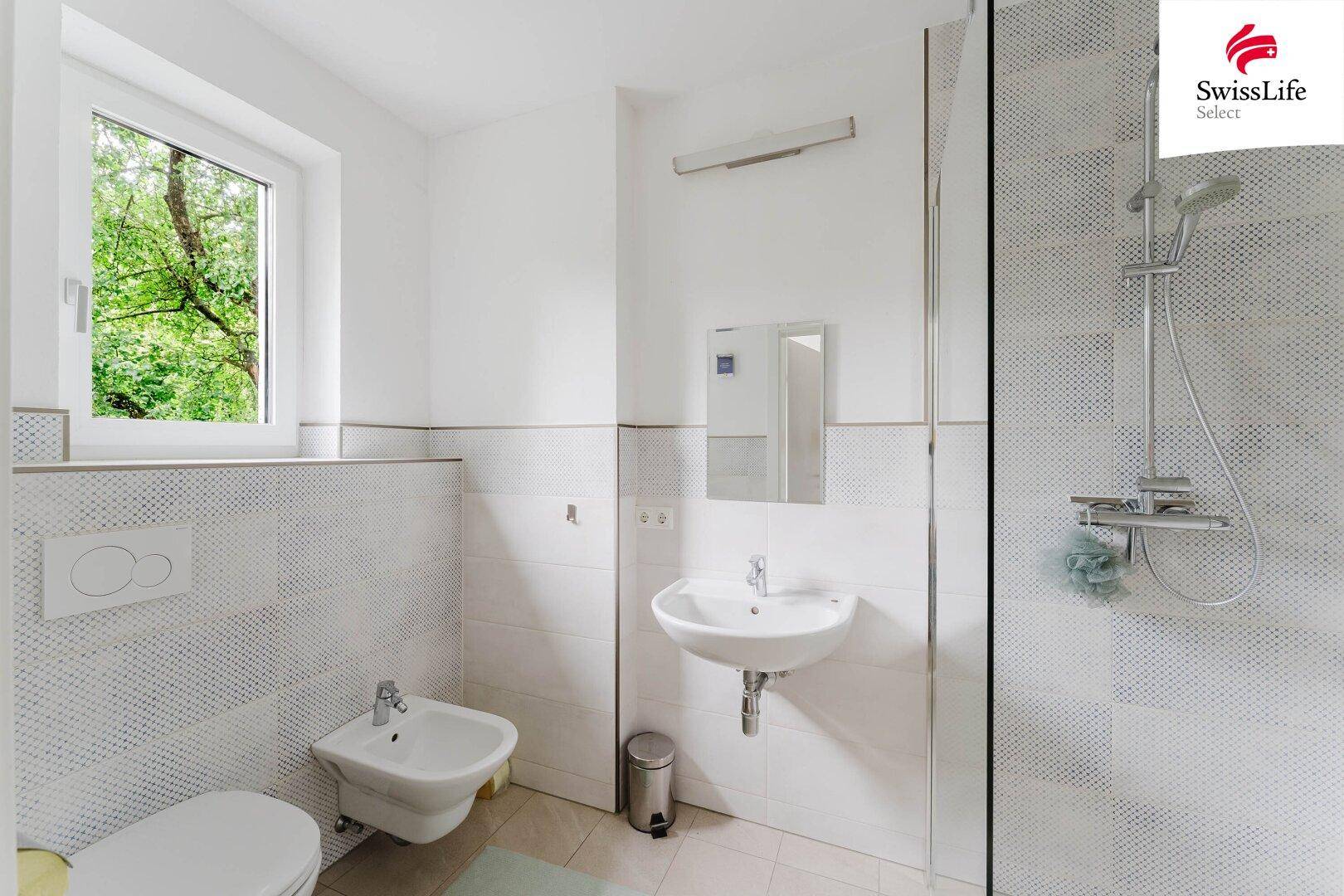 Modernes Badezimmer mit Dusche, Bidet, Waschbecken und Fenster.