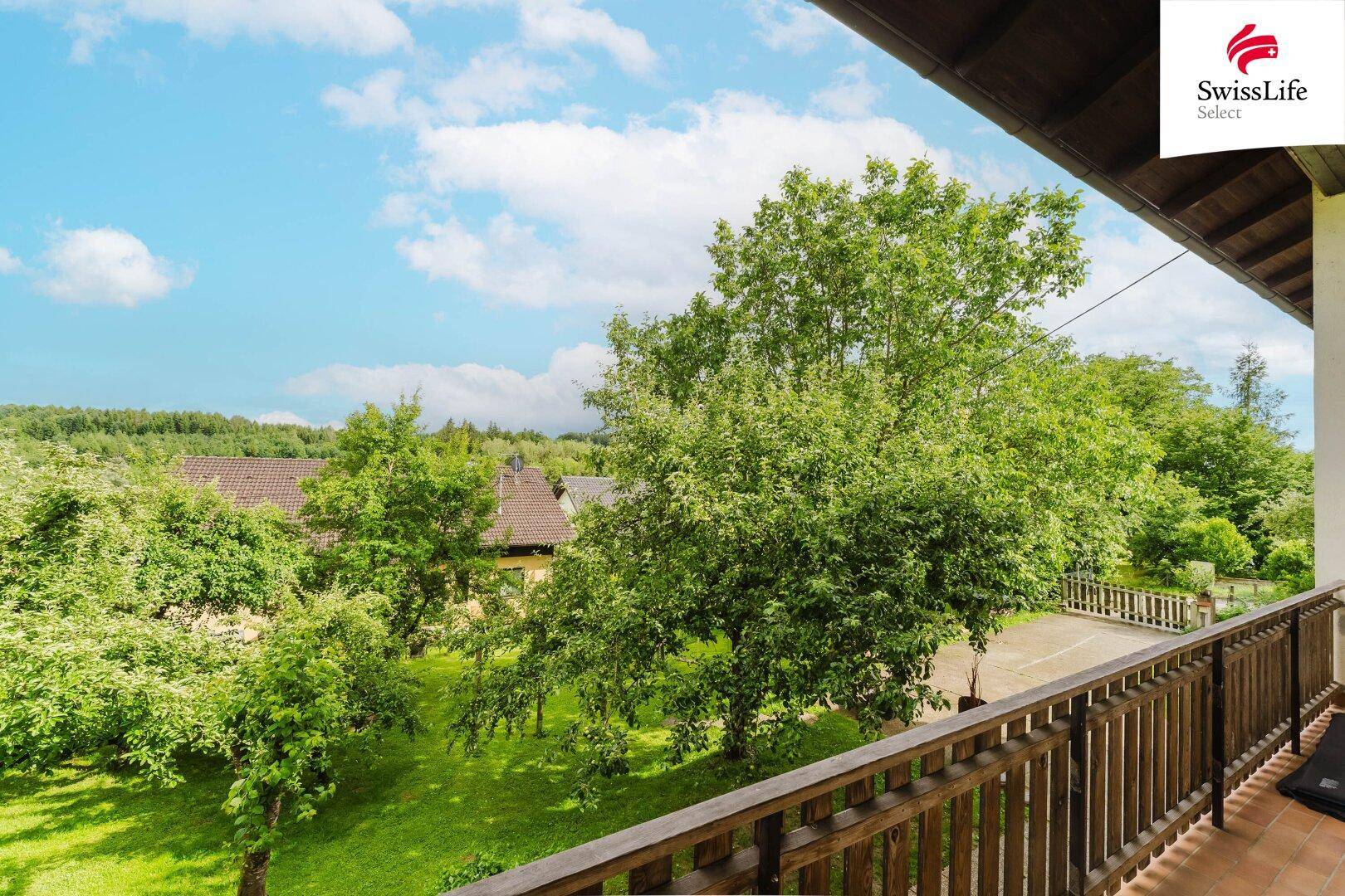 Balkon mit Holzgeländer und weitem Blick über die grüne Landschaft.