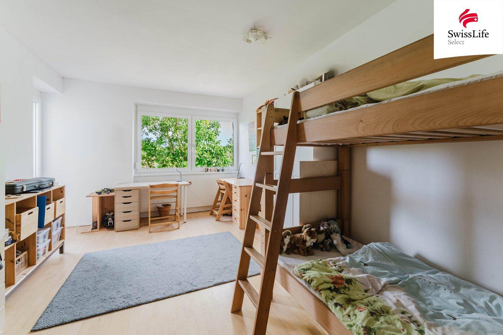 Kinderzimmer mit Etagenbett, Schreibtischen und hellem Holzboden.