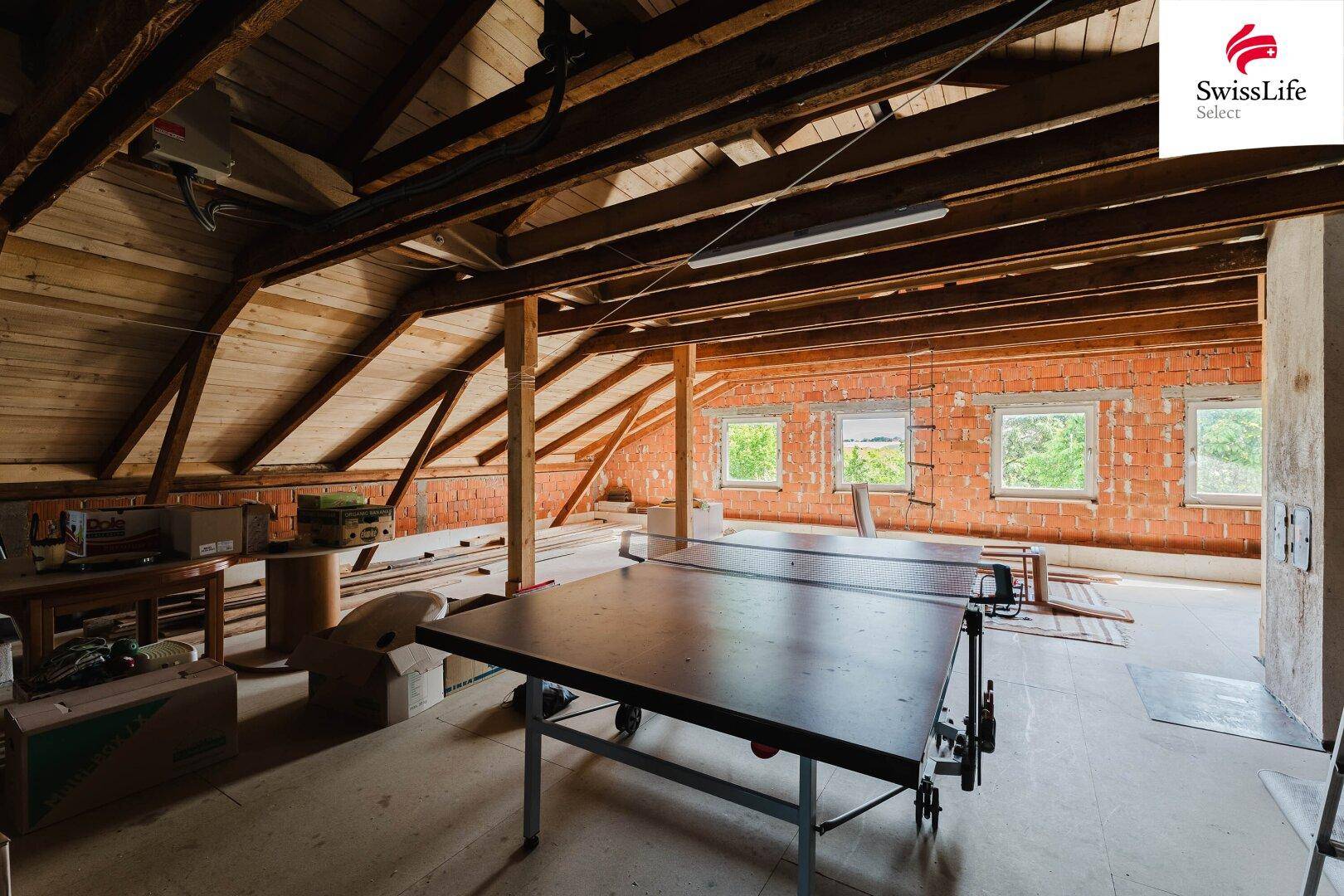 Geräumiger Dachboden mit sichtbaren Holzbalken und Tischtennisplatte.