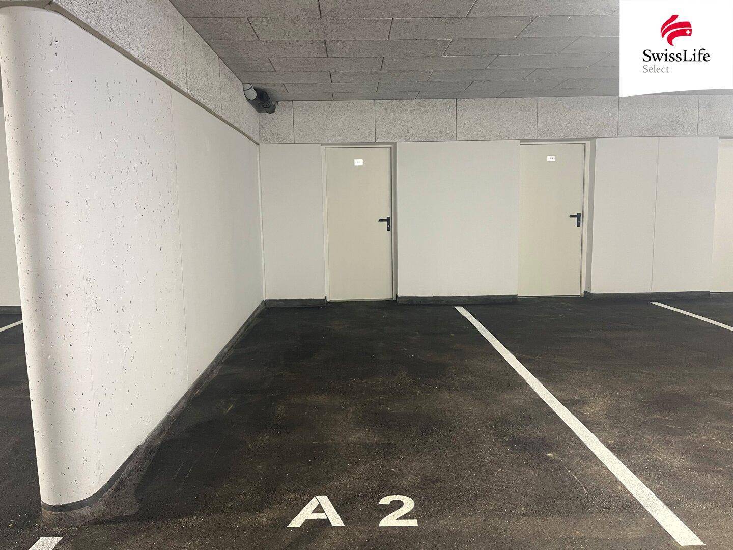 Tiefgaragenstellplatz mit markierter Parkfläche und Zugangstüren zu den Kellerräumen.