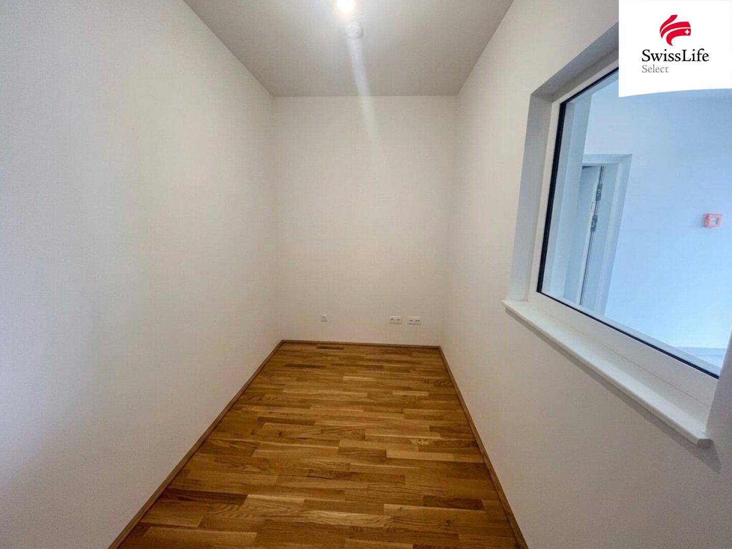 Kleiner, heller Raum mit Holzboden und Fenster, ideal als Büro oder Abstellraum.