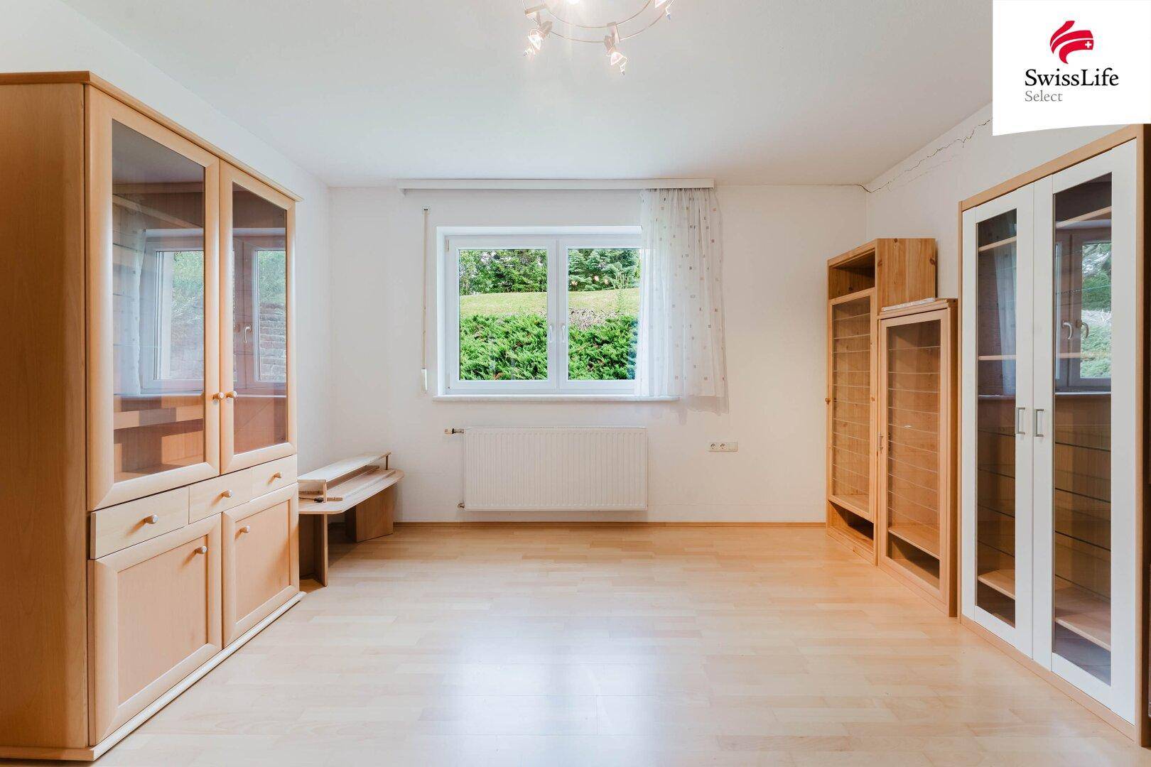 Helles Zimmer mit Holzschränken, Parkettboden und Blick ins Grüne.