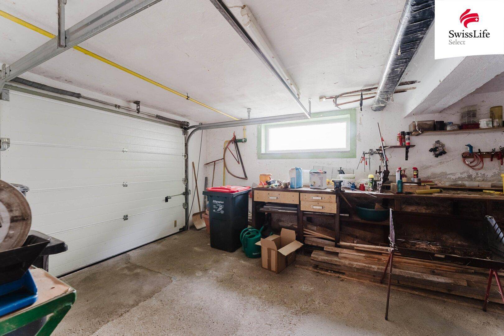 Geräumige Garage mit Werkbank, Fenster und Stauraum für Geräte.