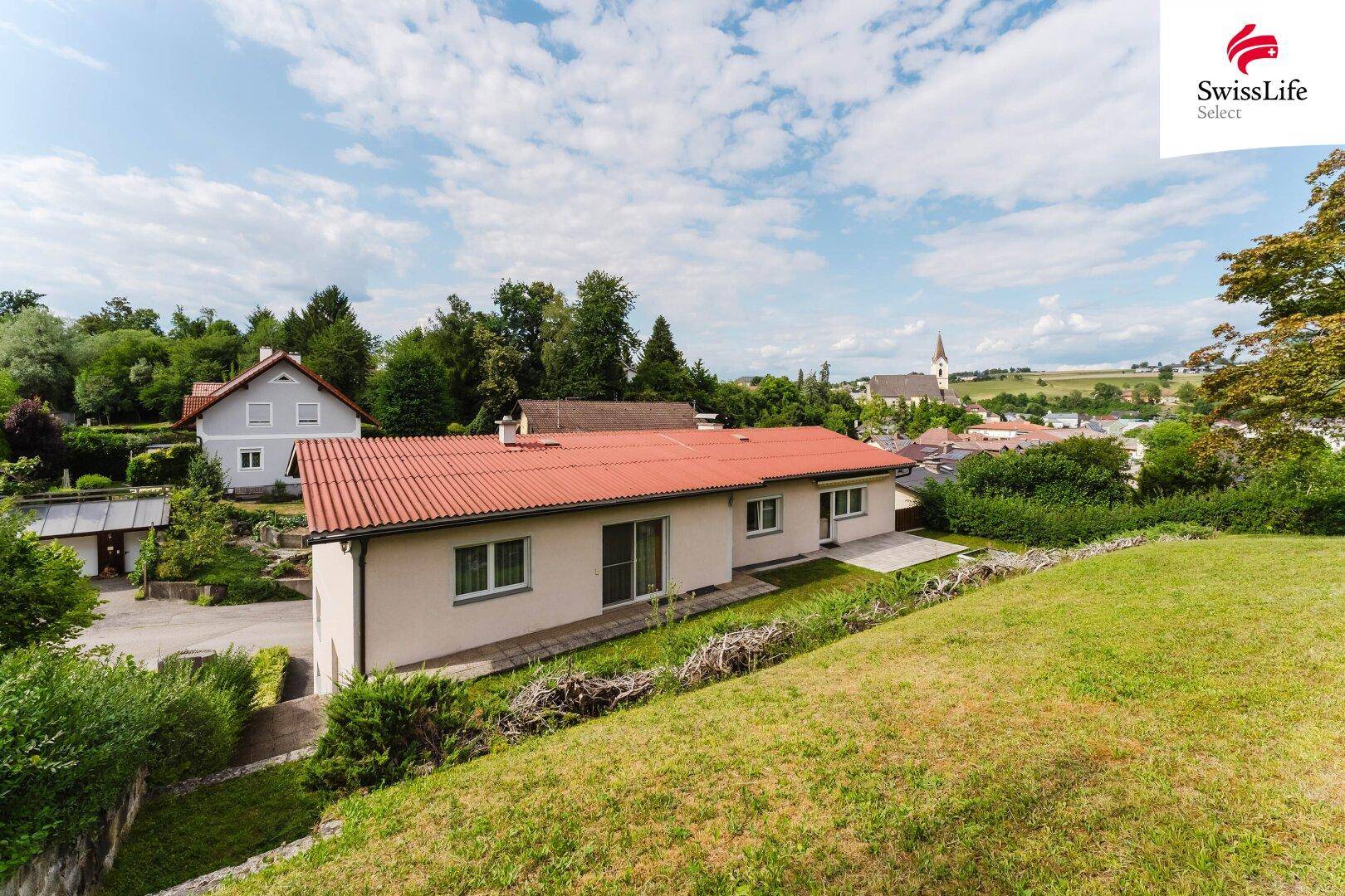 Rückansicht des Hauses mit rotem Ziegeldach und weitem Blick über die Landschaft und ein Dorf.
