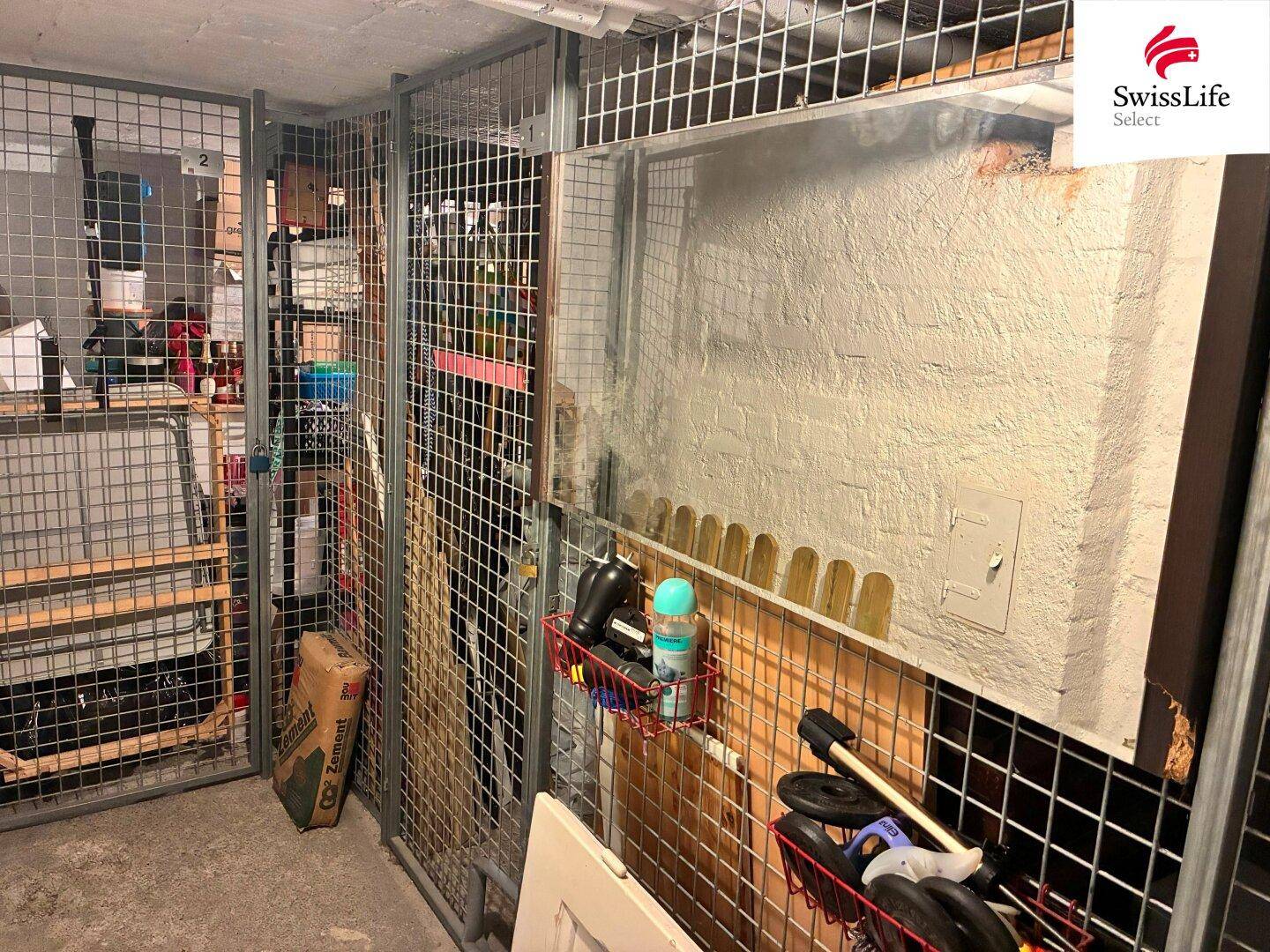 Weitere Kellerabteile mit Gitterwänden und verschiedenen gelagerten Gegenständen, gut organisiert.