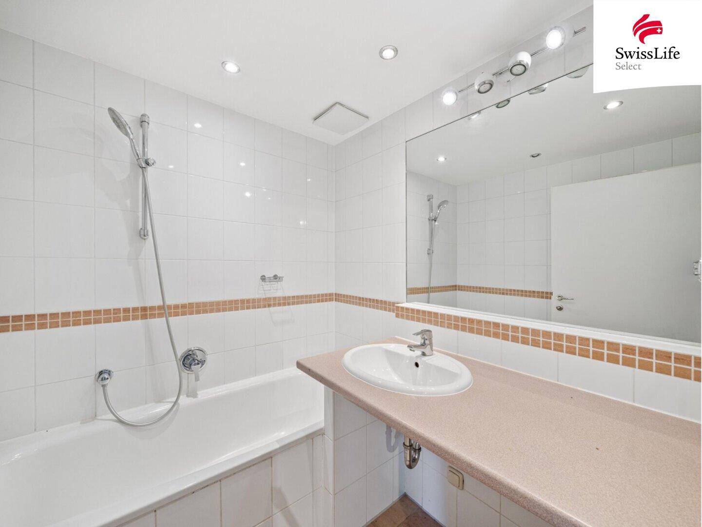 Funktionales Badezimmer mit Badewanne, Einzelwaschbecken und hellen Wandfliesen.