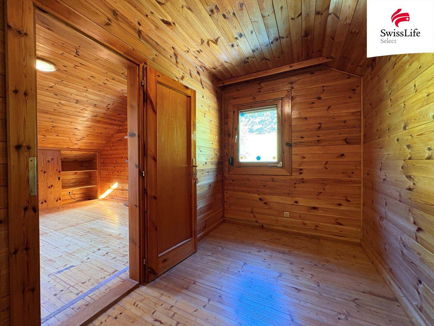 Schlafzimmer im Dachgeschoss mit Holzböden, Holzverkleidung an Wänden und Decke.