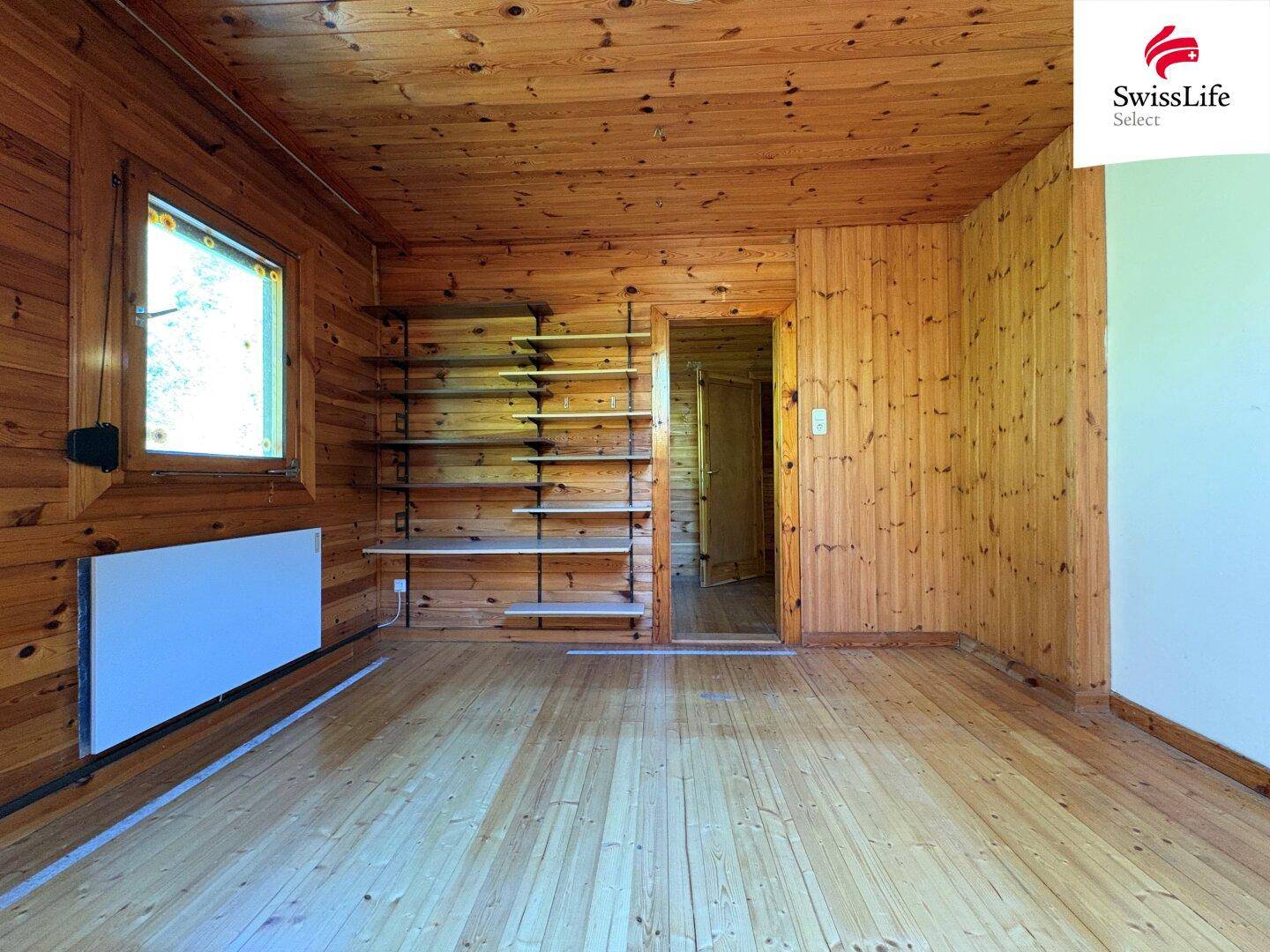 Helles Schlafzimmer mit Holzverkleidung, Holzboden und eingebauten Regalen.