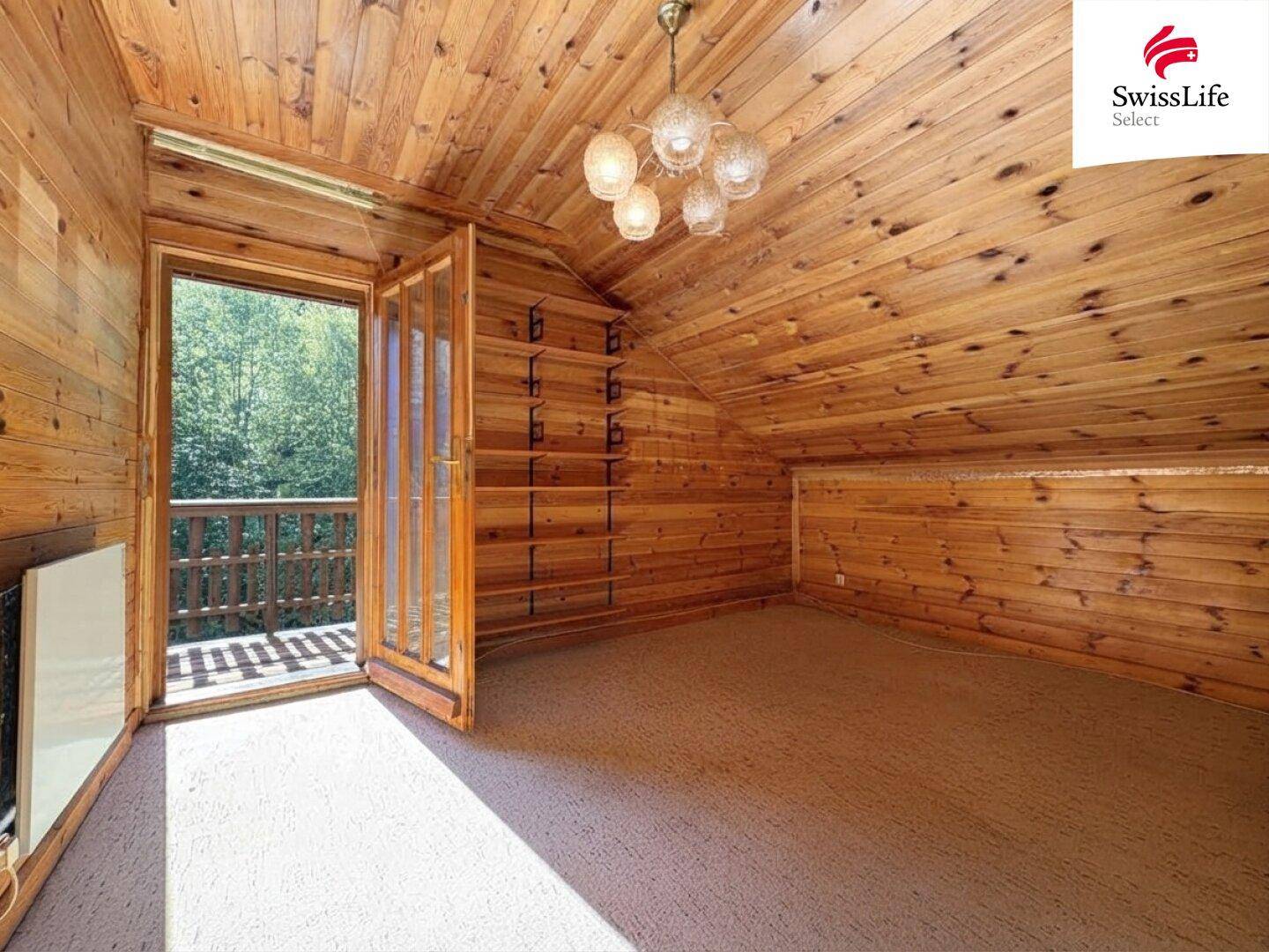 Schlafzimmer mit Holzverkleidung, Teppichboden und Zugang zu einem Balkon.