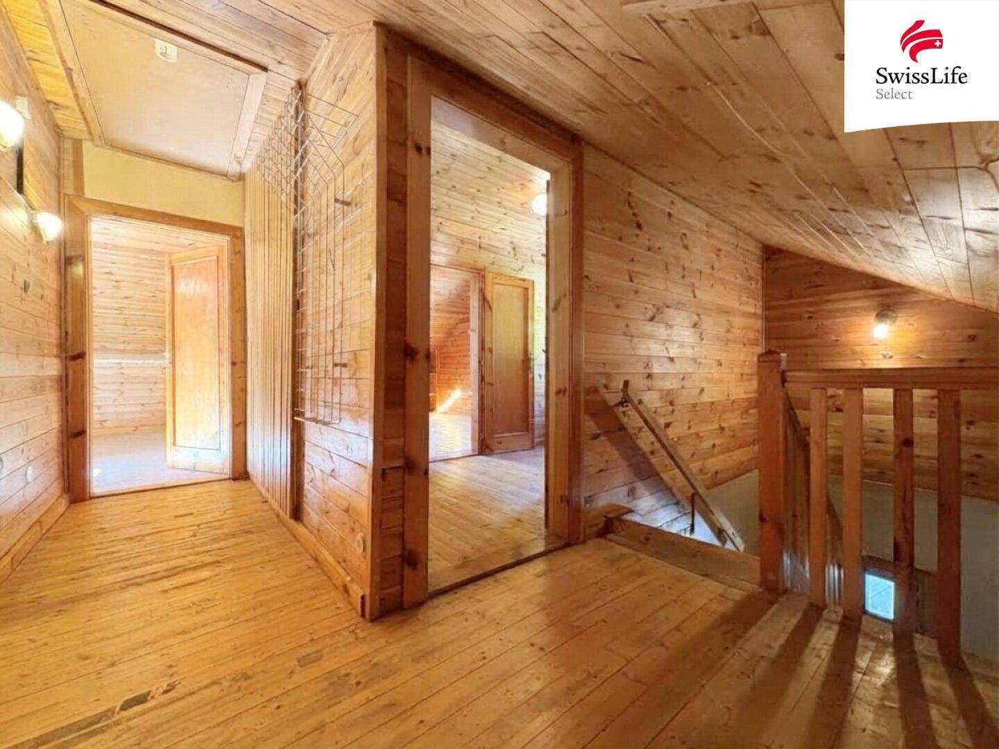 Heller Flur im Obergeschoss mit Holzverkleidung, Holzboden und Blick auf weitere Räume.