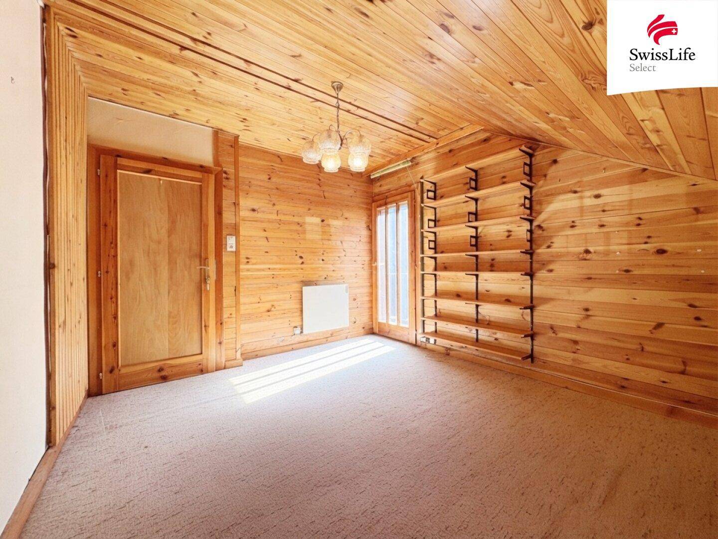 Gemütliches Schlafzimmer mit Holzverkleidung, Teppichboden und eingebauten Regalen.