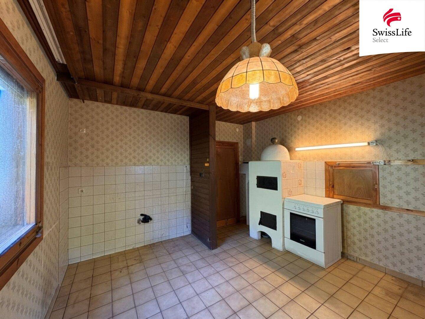 Küche mit Fliesenboden, traditionellem Ofen und Platz für eine Einbauküche.