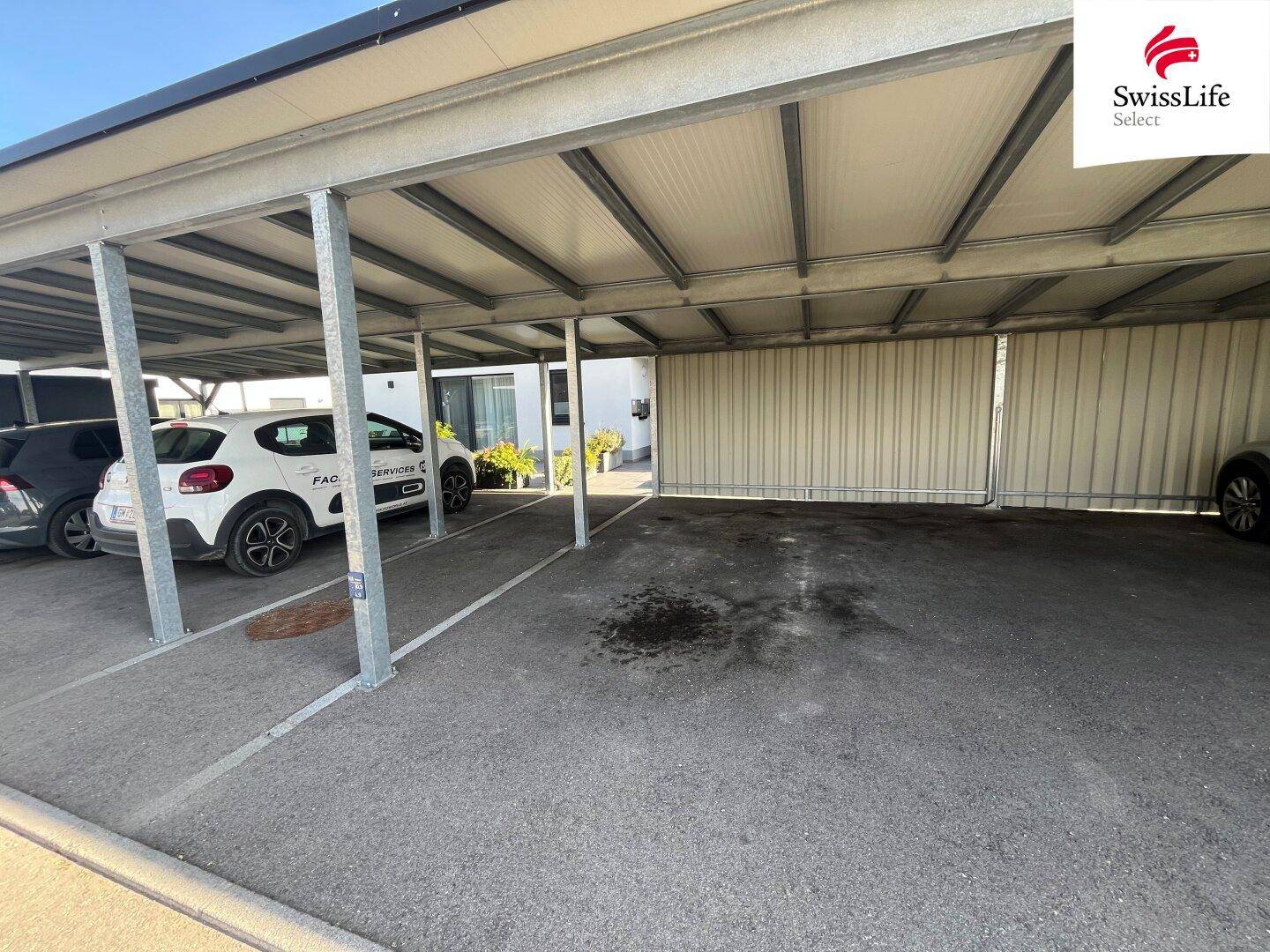 Überdachter Parkplatz (Carport) für mehrere Fahrzeuge neben dem Gebäude.
