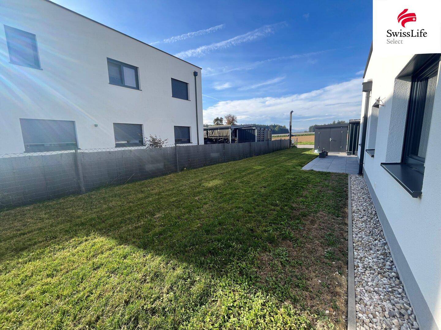 Gepflegter Gartenbereich mit Rasenfläche und Kiesstreifen entlang der Hauswand.