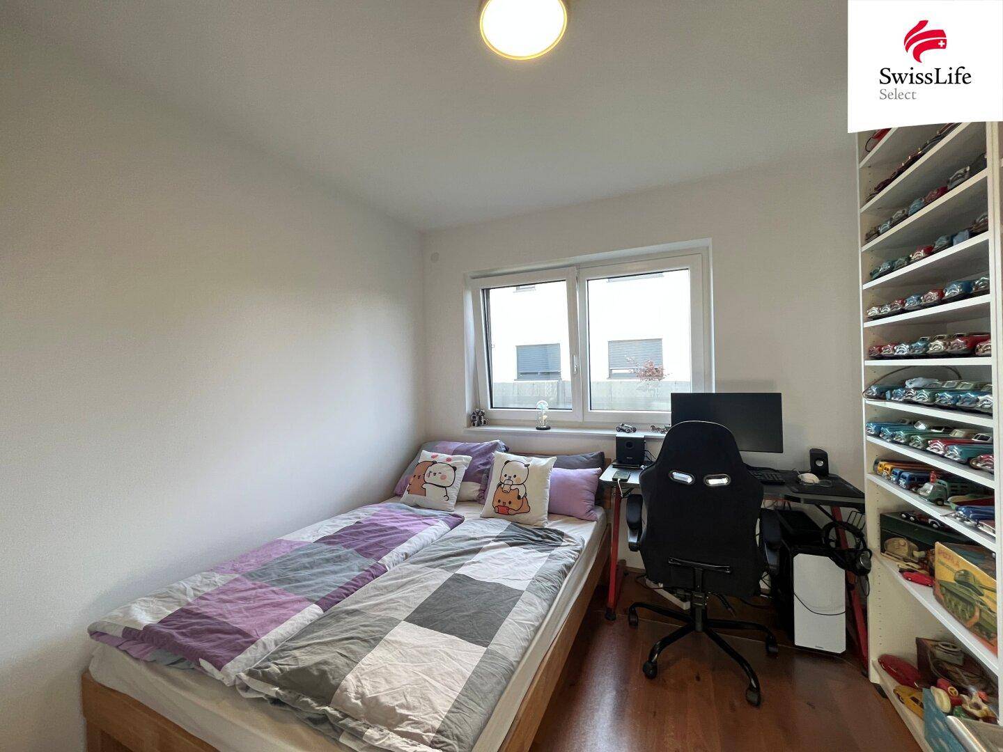 Kinderzimmer mit Einzelbett, Schreibtisch und Regal für Sammlerstücke.