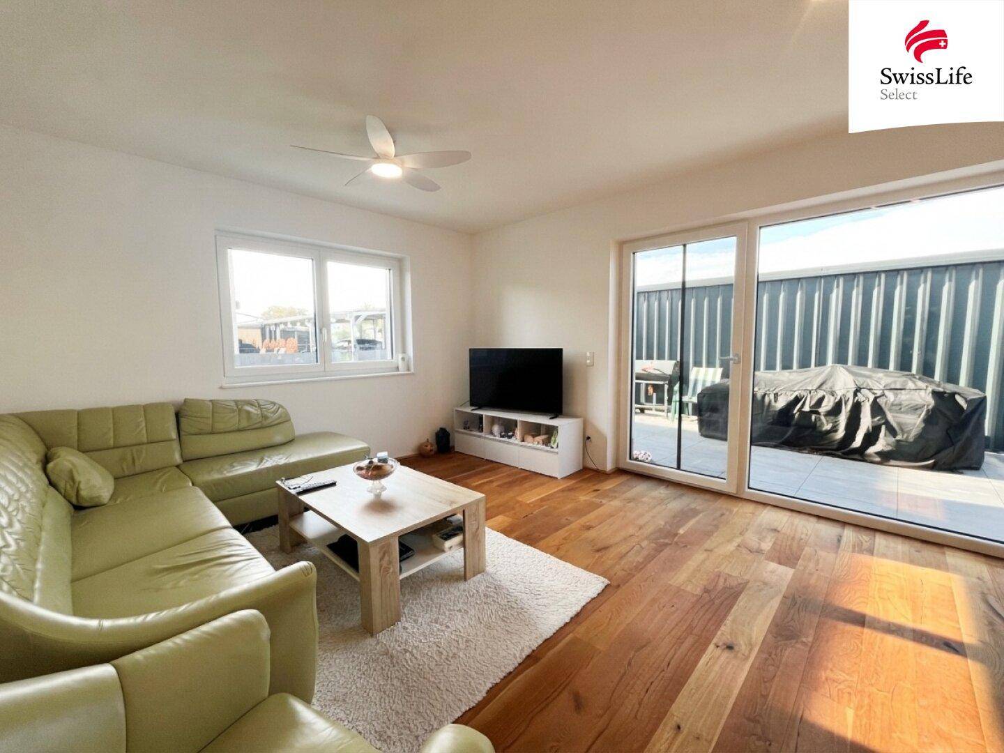 Helles Wohnzimmer mit Holzboden, bequemer Eckcouch und Zugang zur Terrasse.