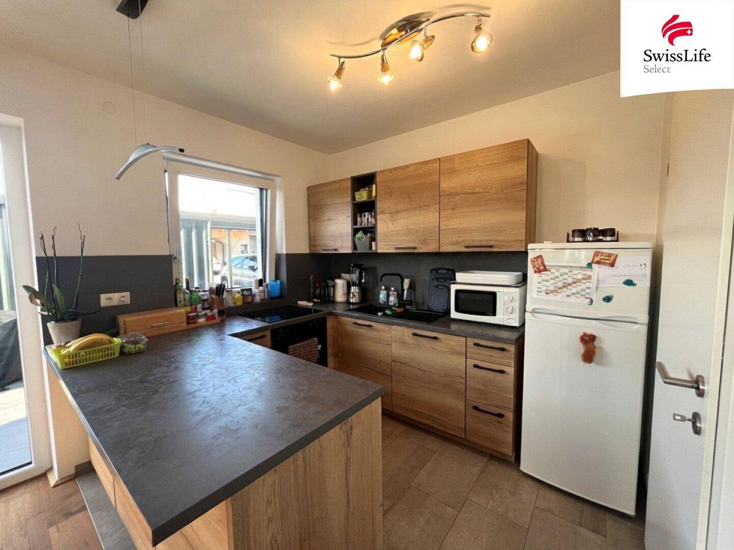 Moderne Küche mit Holzschränken, dunkler Arbeitsplatte und integrierten Geräten.