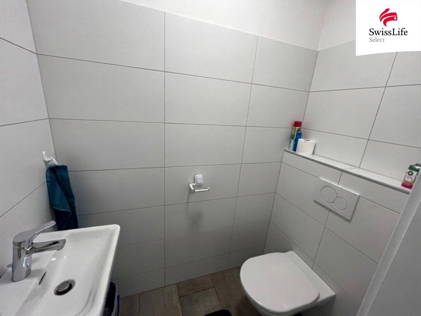 Kleines Gäste-WC mit Wand-WC und Waschbecken, komplett gefliest.