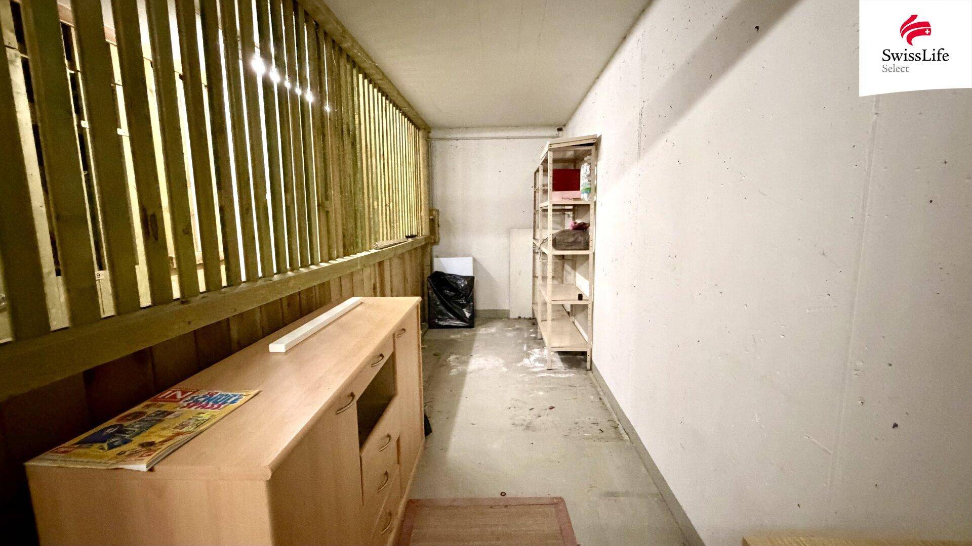 Kellerraum mit Holzverkleidung, Regal und Betonboden für zusätzlichen Stauraum.