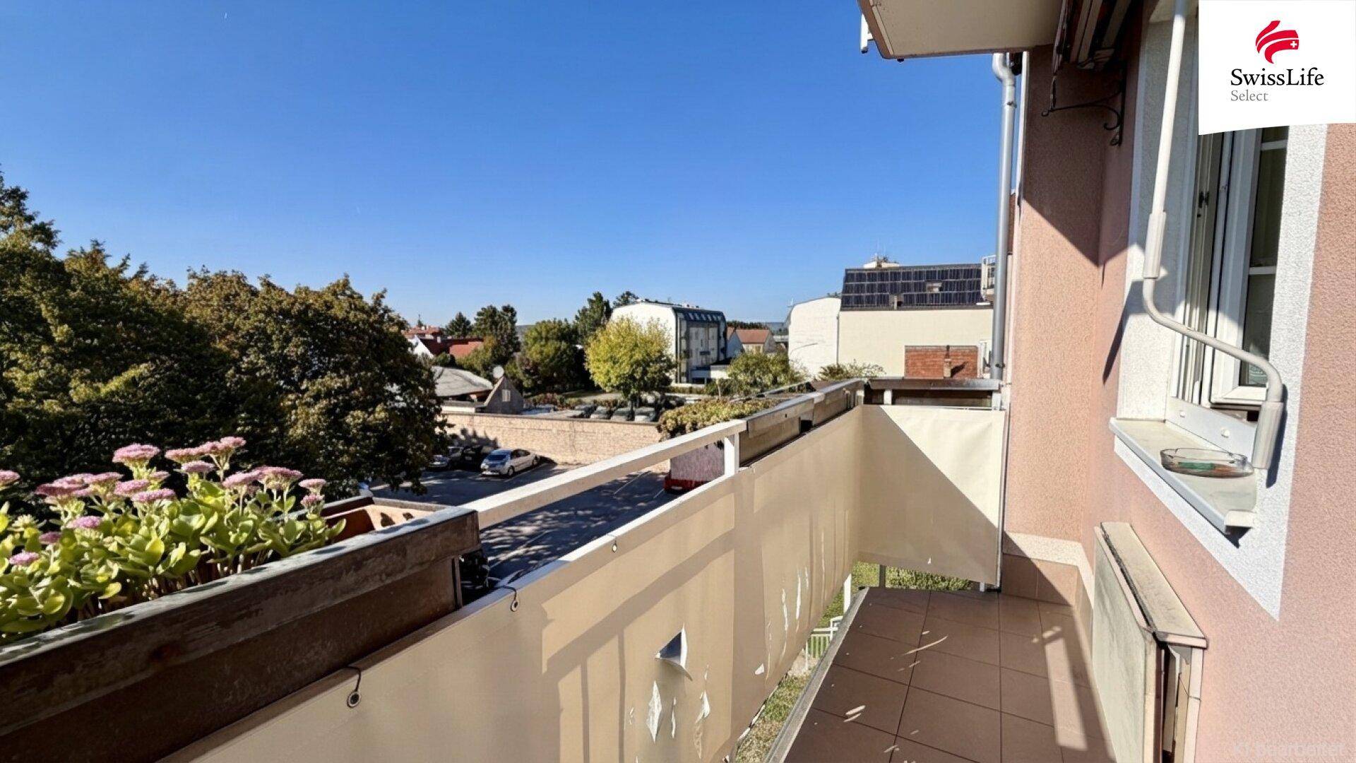 Balkon mit Fliesenboden, Sichtschutz und Blick auf die Straße und parkende Autos.