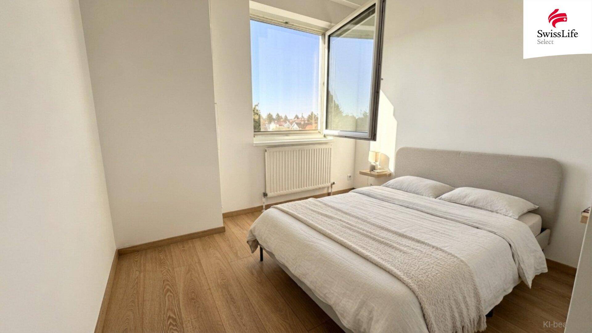 Helles Schlafzimmer mit Holzboden, großem Fenster und einem Doppelbett.
