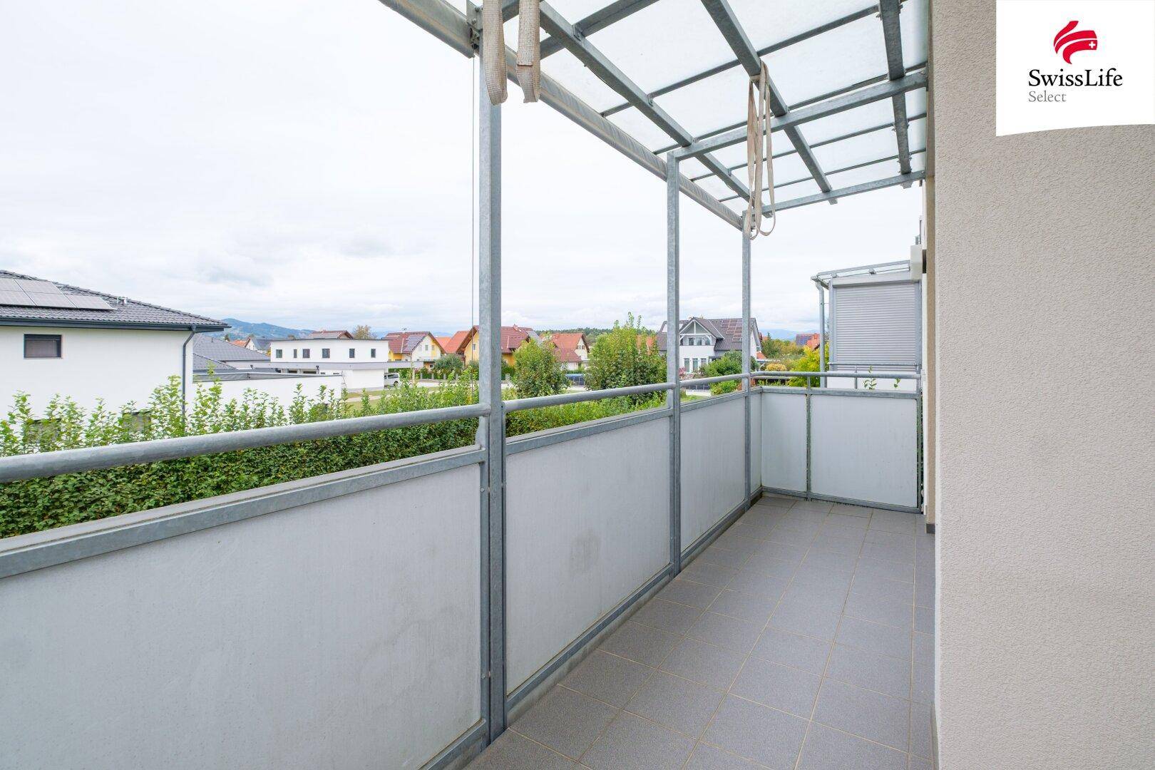 Geräumiger Balkon mit Überdachung, Fliesenboden und weitem Blick ins Grüne.