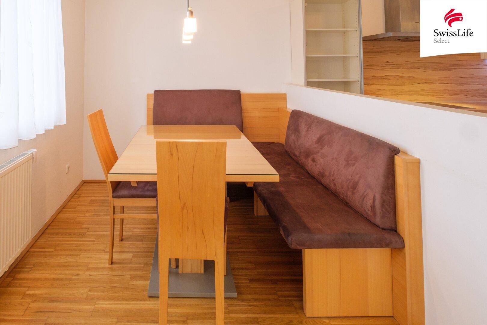 Gemütlicher Essbereich mit Holztisch, Sitzbank und Parkettboden, angrenzend an die Küche.