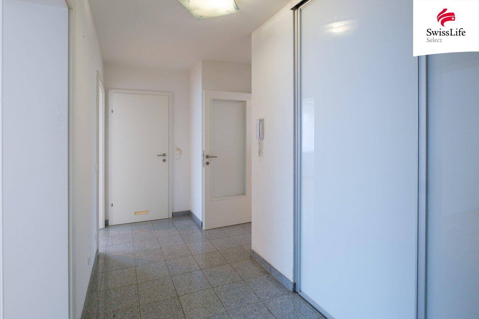 Heller Flur mit Fliesenboden, weißen Wänden und praktischen Einbauschränken.