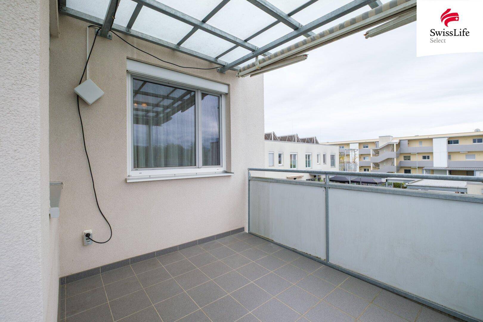 Überdachter Balkon mit Fliesenboden und Blick auf die Umgebung, ideal für entspannte Stunden.