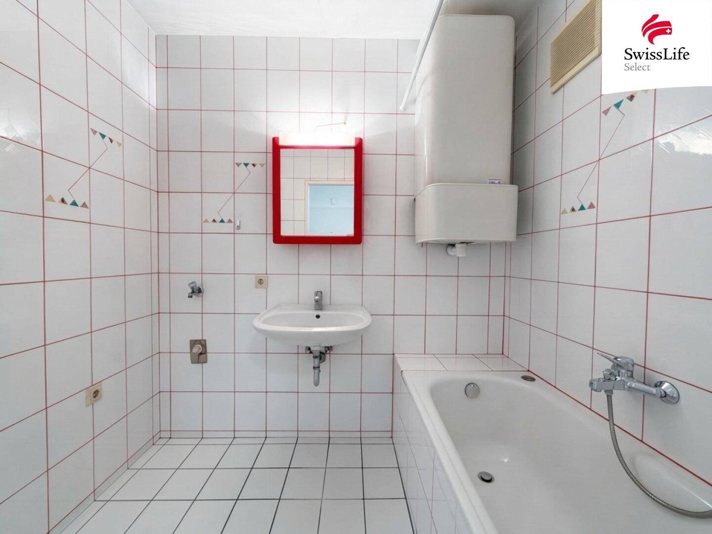 Badezimmer mit weißen Fliesen, Badewanne und einem roten Spiegelschrank.